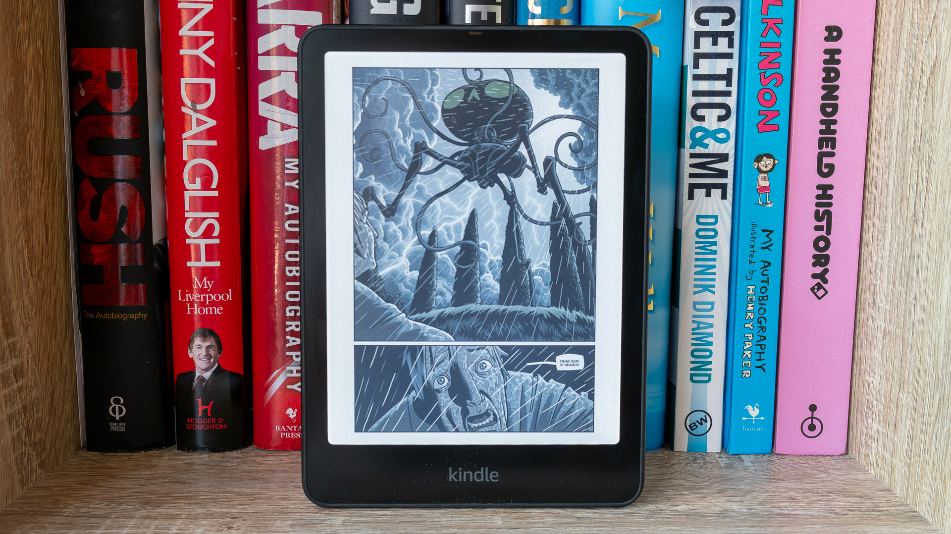 Kindle Colorsoft Signature Edition in front of books (and showing coming book page)