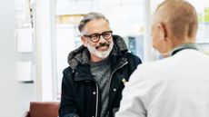 A cheerful customer picks up prescription drugs from the pharmacist.