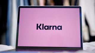 Klarna logo in black lettering against a pink background pictured on a laptop screen.