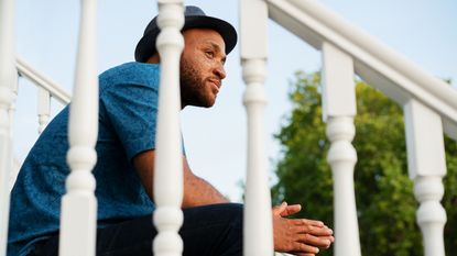 An older man sits on some porch steps and does some thinking.