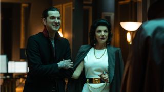 Ben Schwartz and Shohreh Aghdashloo standing together in an office, meeting Dracula in Renfield.