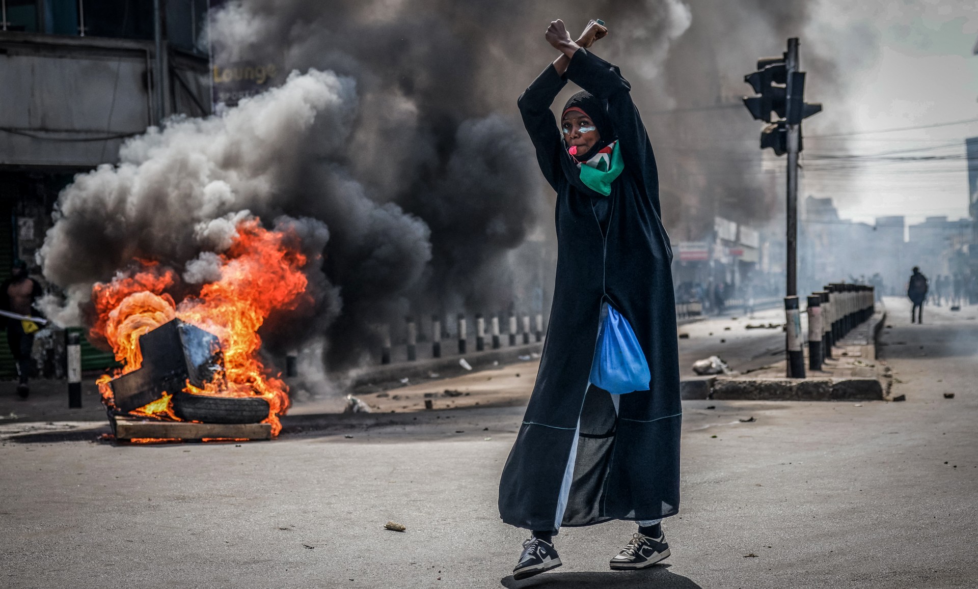 A protester reacts in front of a burning barricade in downtown Nairobi