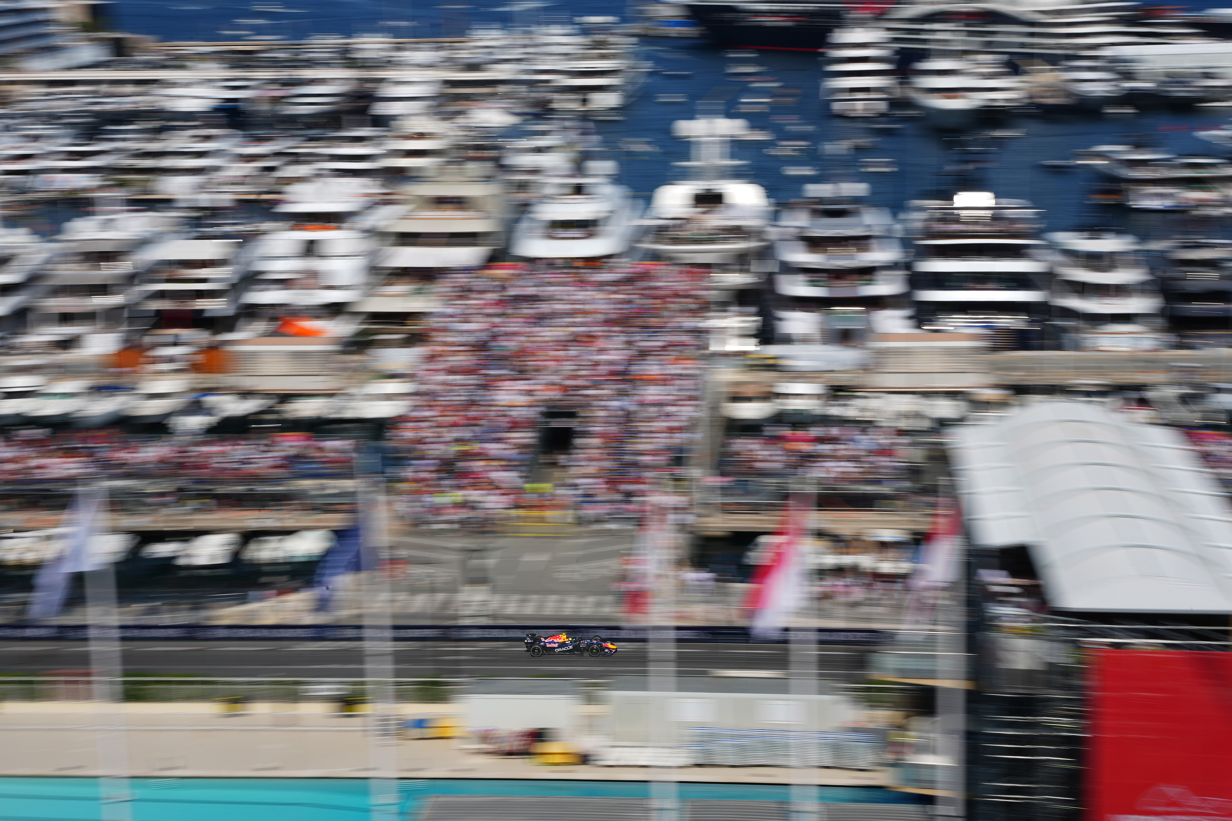 Red Bull race car speeding past a line of yachts in Monaco harbour