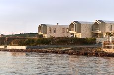 views of Pur residential recording studio, a family of structures in a cluster, made of stone and wood against blue mediterranean skies