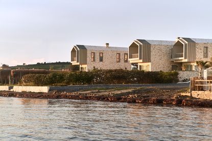 views of Pur residential recording studio, a family of structures in a cluster, made of stone and wood against blue mediterranean skies