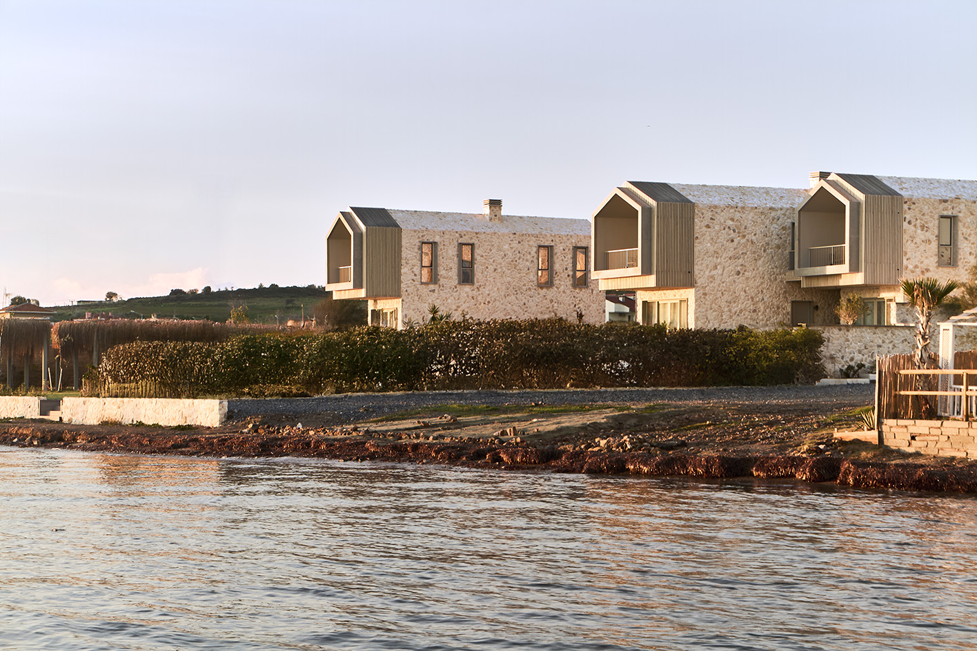 views of Pur residential recording studio, a family of structures in a cluster, made of stone and wood against blue mediterranean skies