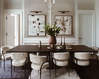 neutral dining room with dark wood table, curved mid century style off white chairs and statement artwork