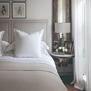 White and grey neutral bed with bedisde table and white curtains