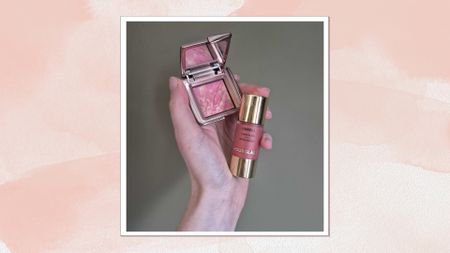 A close-up of Digital Beauty Writer, Naomi Jamieson holding the Hourglass Unreal Liquid Blush and Hourglass Ambient Lighting Blush palette in her hand, in front of a dark green backdrop/ and in a pink watercolour paint-style template