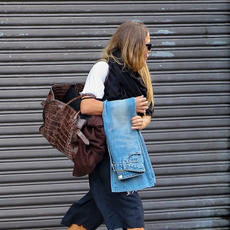 An image of Mary-Kate Olsen out in New York wearing Adidas trainers with long shorts and a white T-shirt. She carries a pair of jeans and an oversized croc bag. 