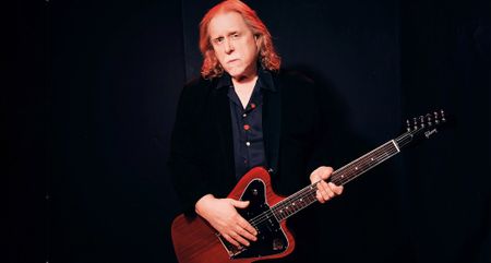 A portrait of Warren Haynes holding a P-90 loaded Gibson Firebird, which the Gov't Mule frontman and Allman Brothers Band alumnus reveals is a future signature model.