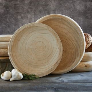 two wooden serving bowls standing upright on a wooden surface