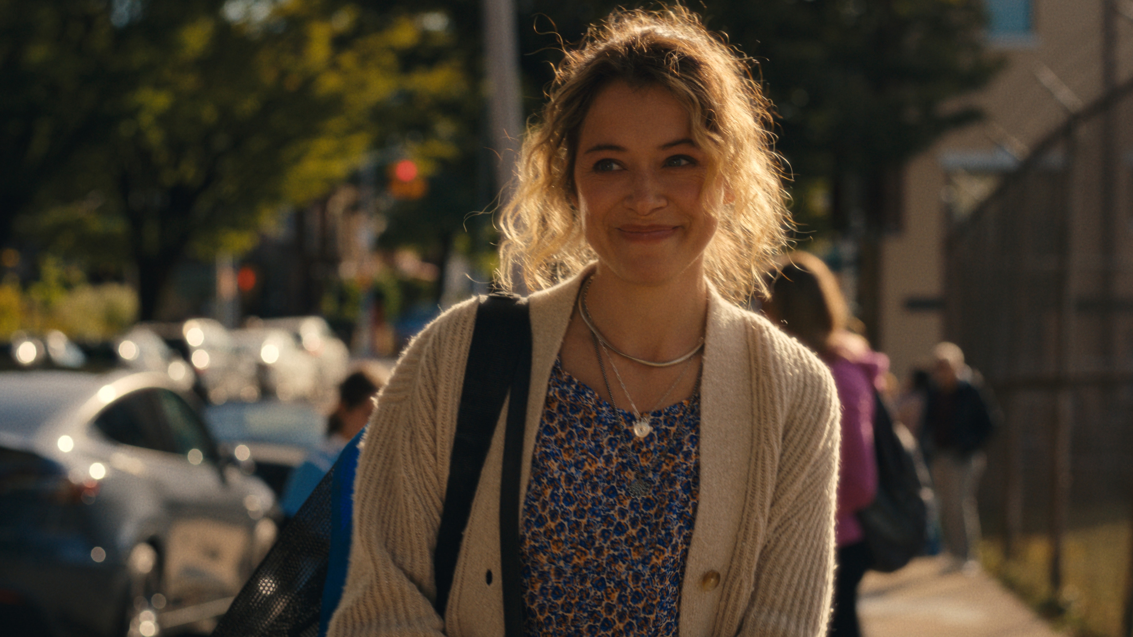 Tatiana Maslany as Paula Saunders smiling and walking down a street.