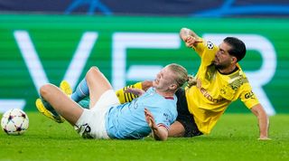 Erling Haaland is challenged by Emre Can during Manchester City's Champions League clash against Borussia Dortmund.