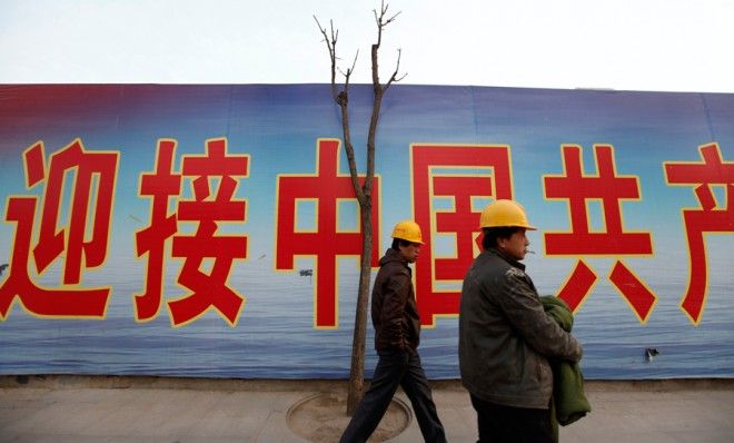 Laborers walk past a banner outside a construction site in Beijing&amp;#039;s central business district on April 14.