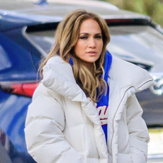 Jennifer Lopez wears light wash flare jeans and a white puffer coat on the set of her upcoming film "Office Romance" in New Jersey.
