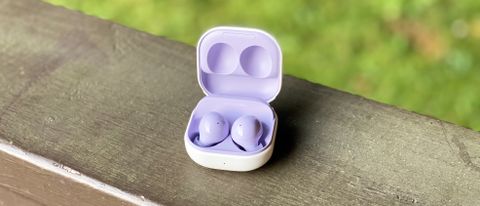 the samsung galaxy buds 2 wireless earbuds in lilac pictured in their charging case on a wooden surface