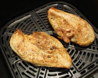 Two cooked and seasoned chicken breasts in Cosori Premium II Plus 6.5 quart air fryer basket