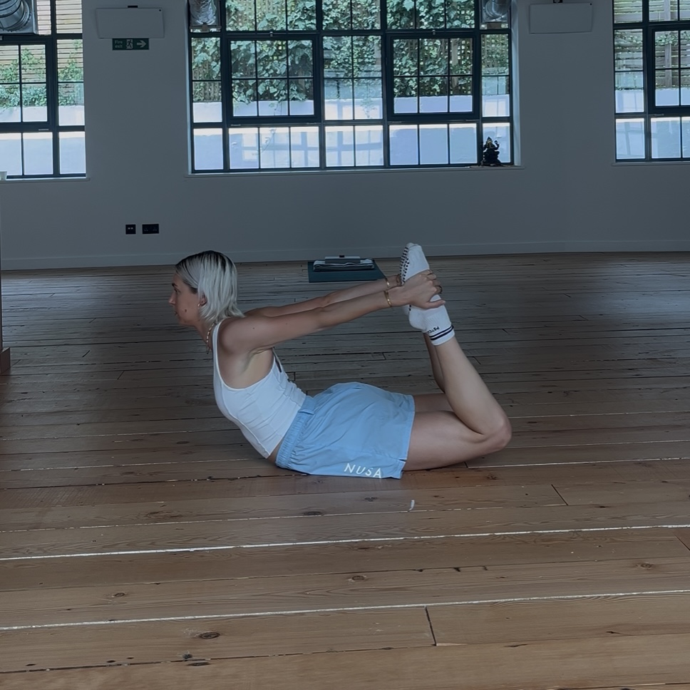 A woman practices a Pilates backbend in a yoga studio