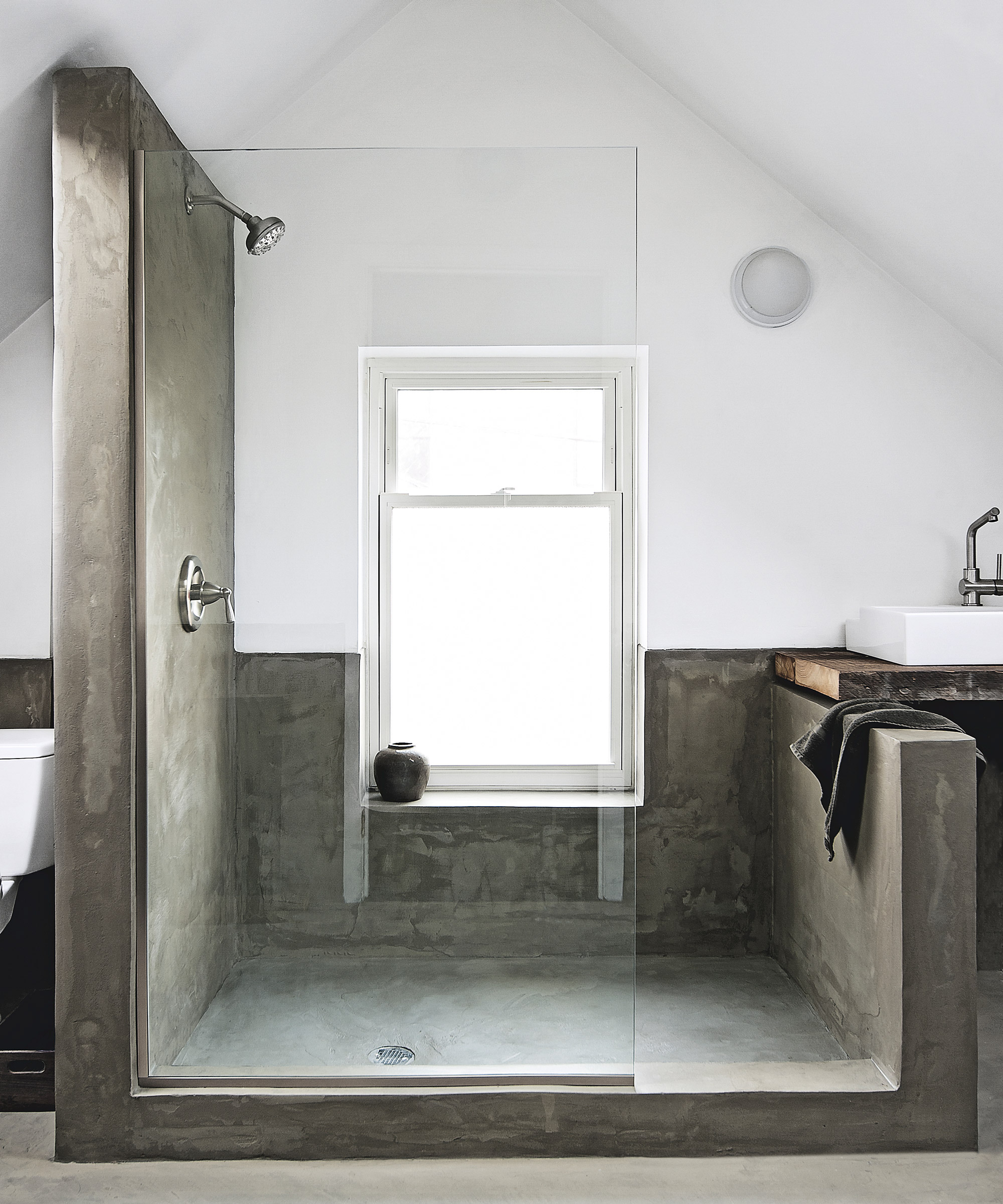 A walk-in shower in a small bathroom with sandblasted glass panelling