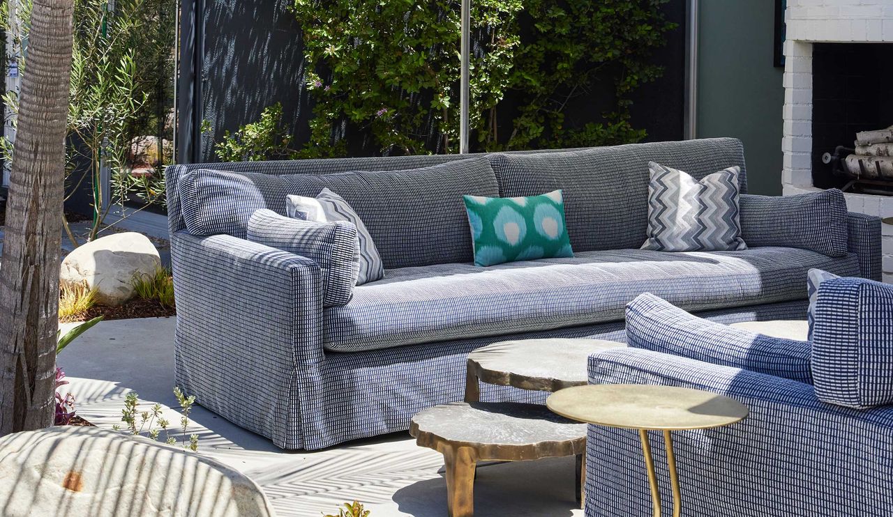 a backyard with an outdoor sofa and tables