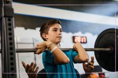 Tween boy lifting weights in the gym