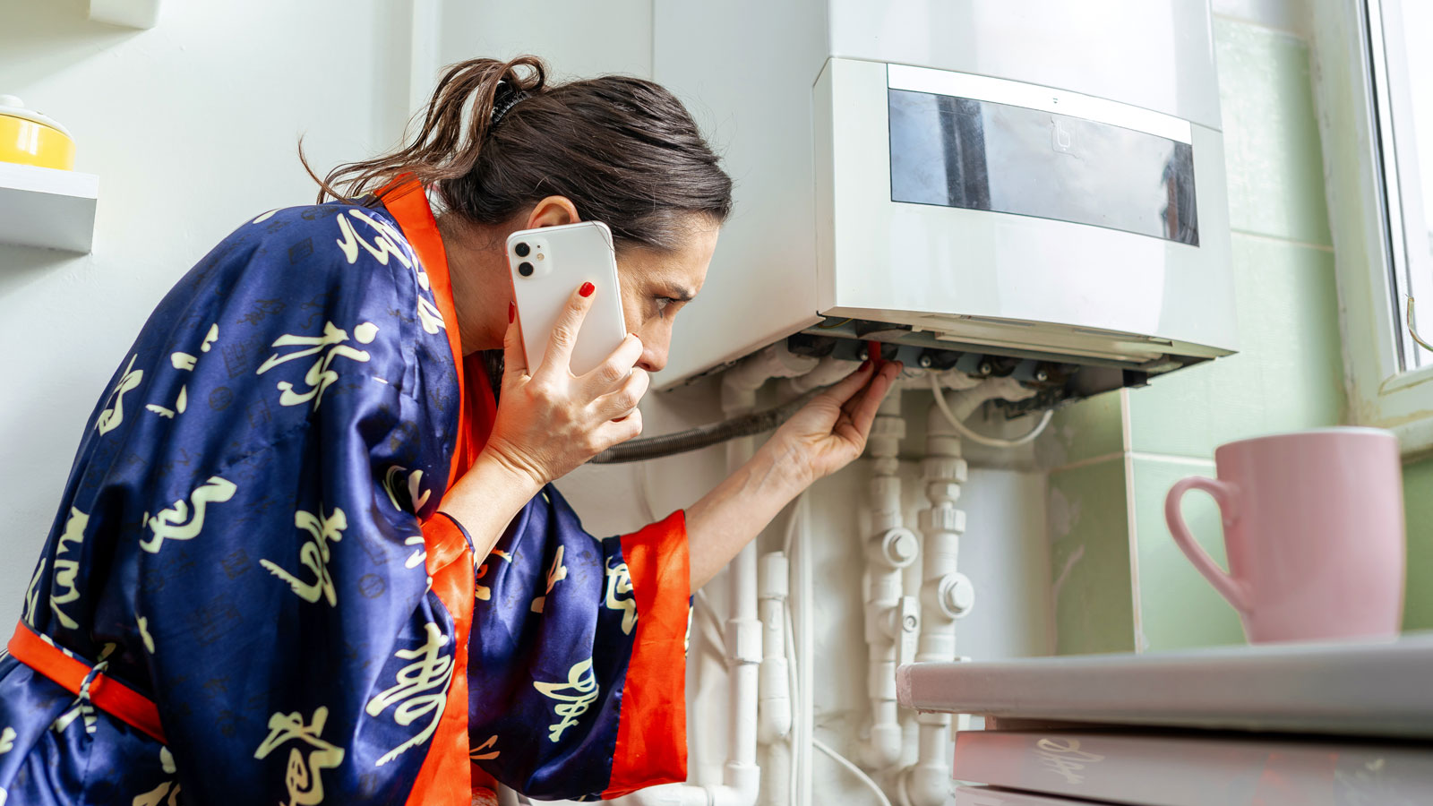 woman in dressing gown trying to fix broken boiler