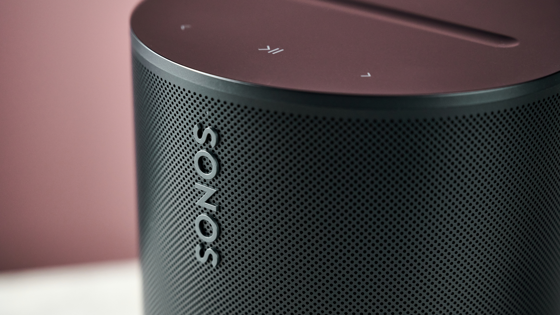 An even closer shot of the Sonos Era 100 SL, showing the Sonos logo on the front and the play/pause and skip buttons on top.