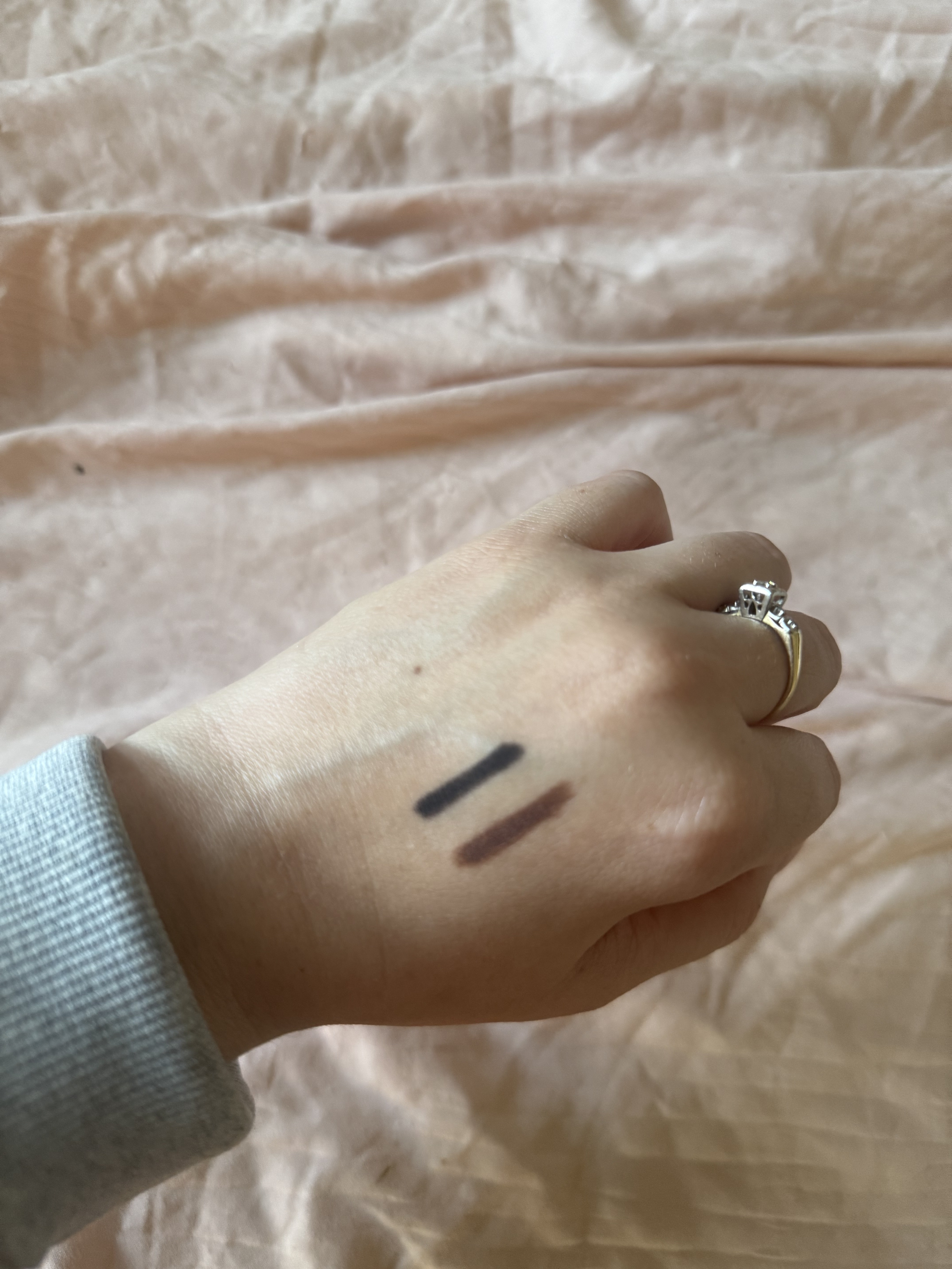 swatches of black and brown urban decay 24/7 glide-on waterproof eyeliner pencil on back of hand