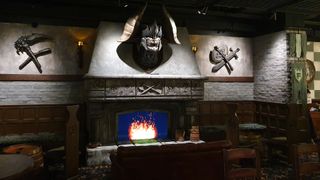 A monstrous head mounted above a fireplace with pixel flame