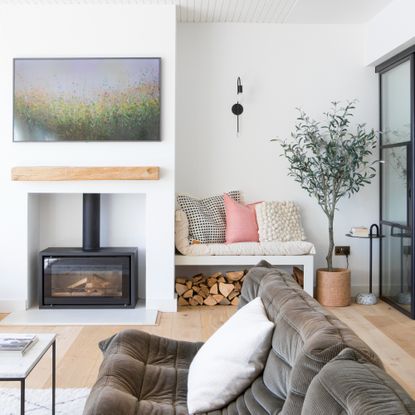 Log burner underneath TV, next to built in bench storing logs underneath