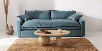 A living room with a blue sofa and a small coffee table on a jute rug