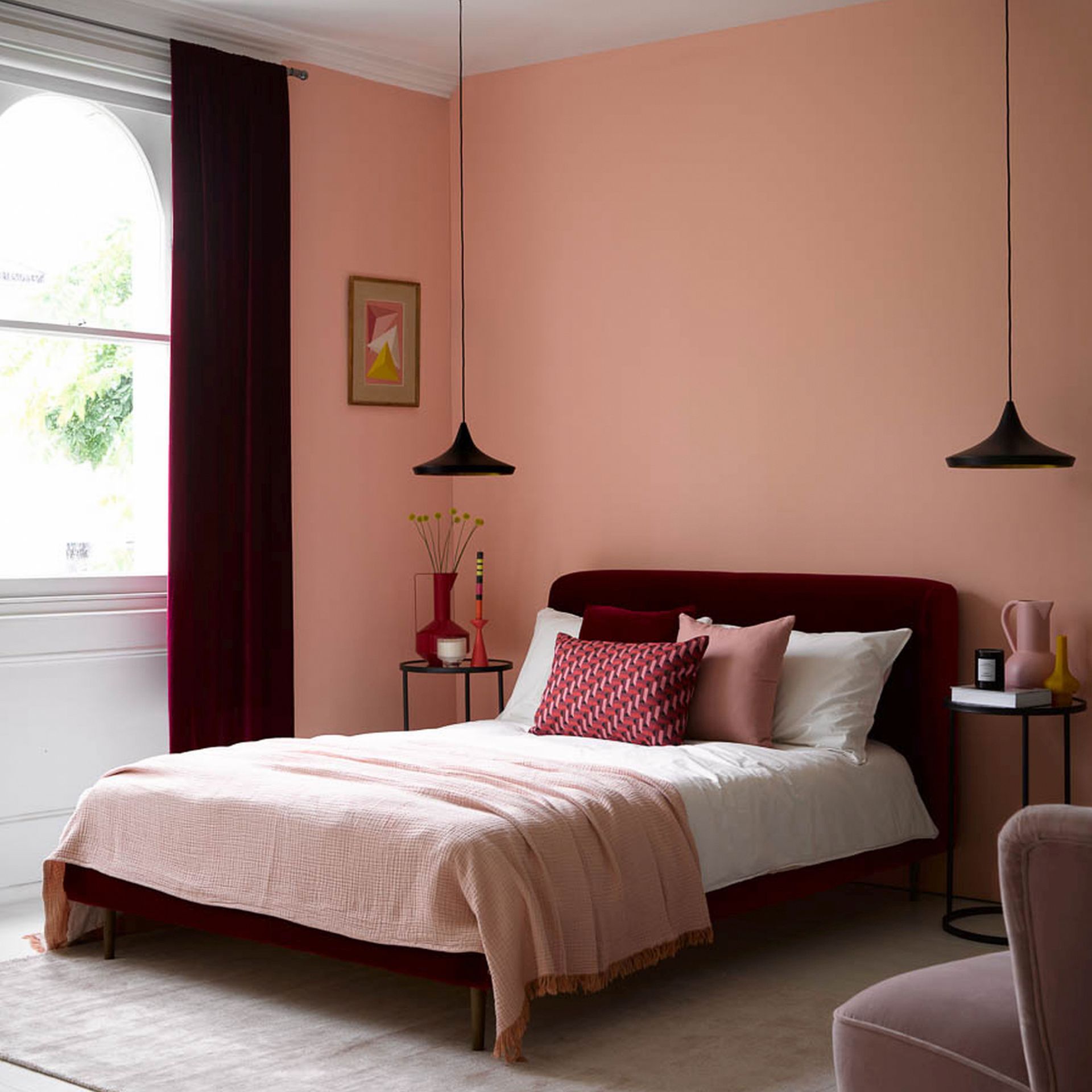 small bedroom color ideas, coral bedroom with velvet claret bed and matching curtains, black pendant lights, red and pink accessories, artwork, black side tables, rug, armchair