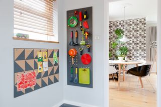 Grey pegboard with brightly coloured utensils hung up on it