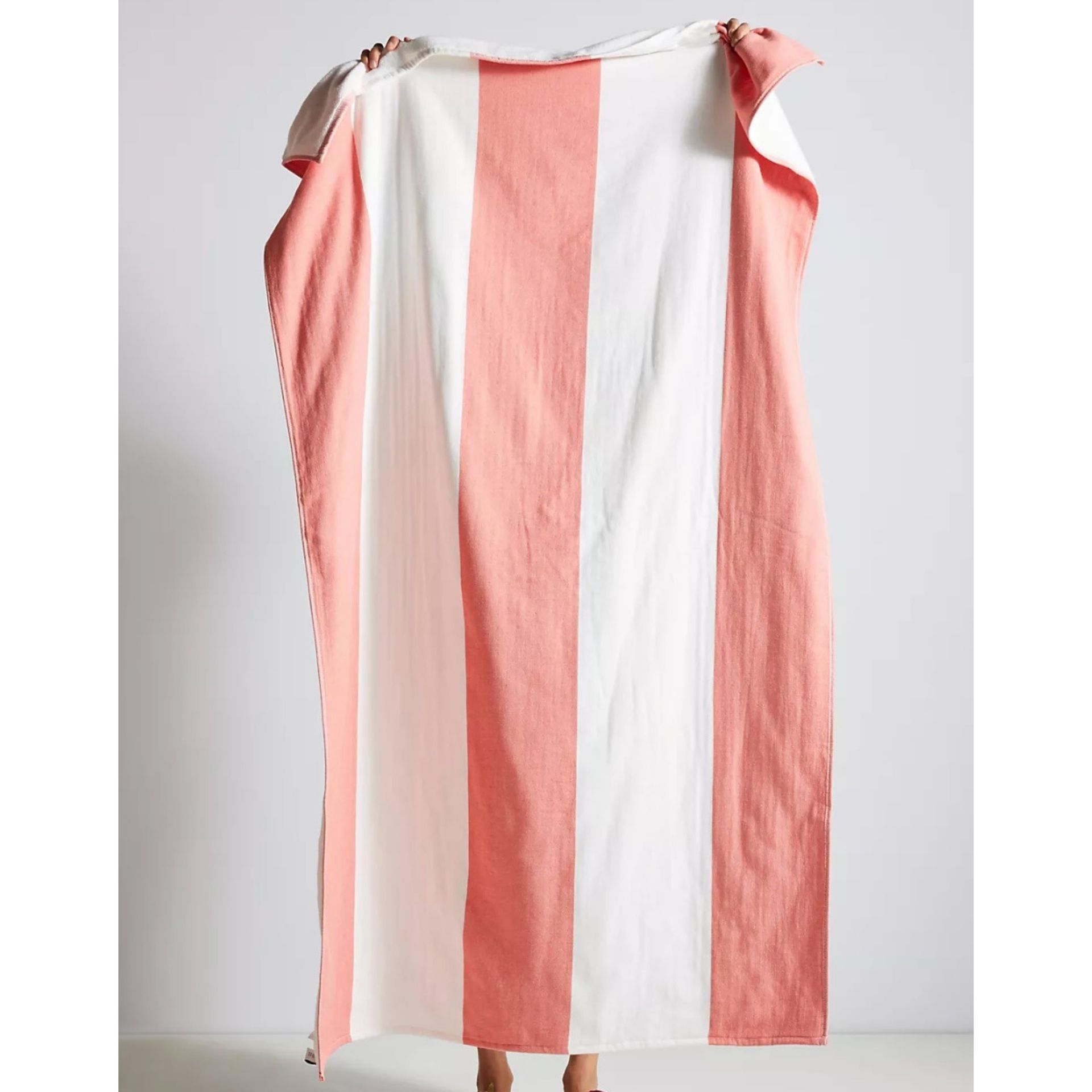 Handuk pantai merah muda dan putih dengan latar belakang putih