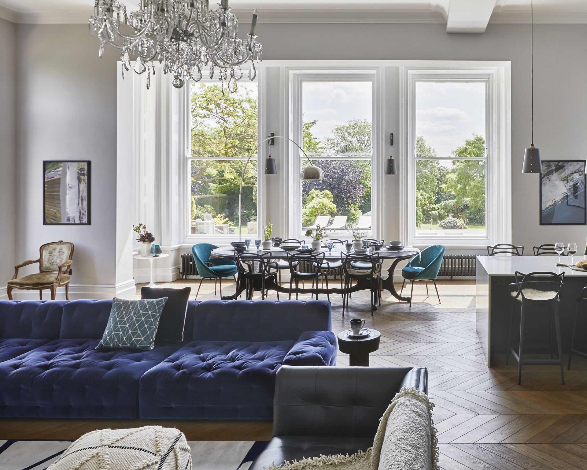 A dining room idea with large open plan kitchen, living and dining areas with large windows and blu sofa and chairs
