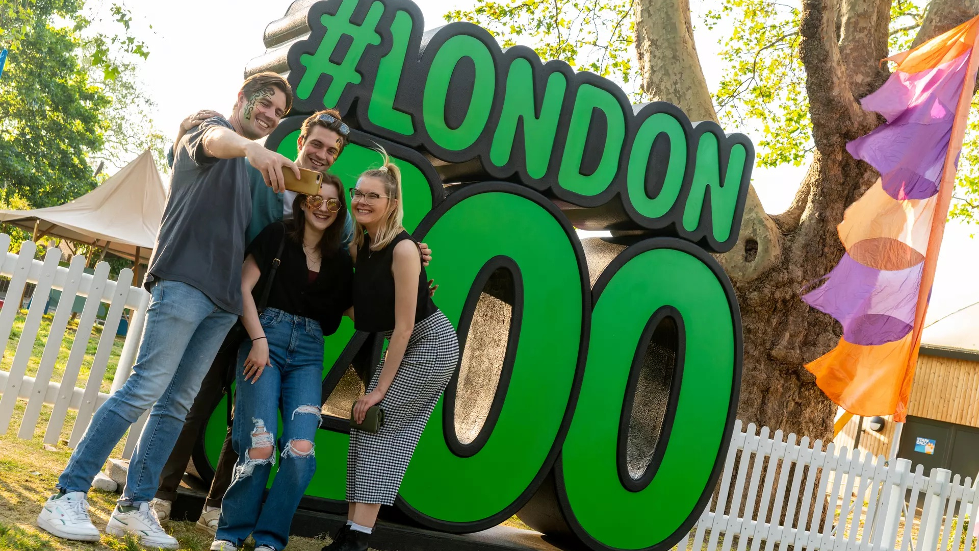 Four people taking a selfie in front of a sign for London Zoo 