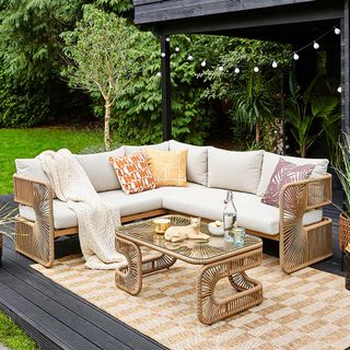 garden decking with rattan outdoor sofa with cream cushions and matching coffee table