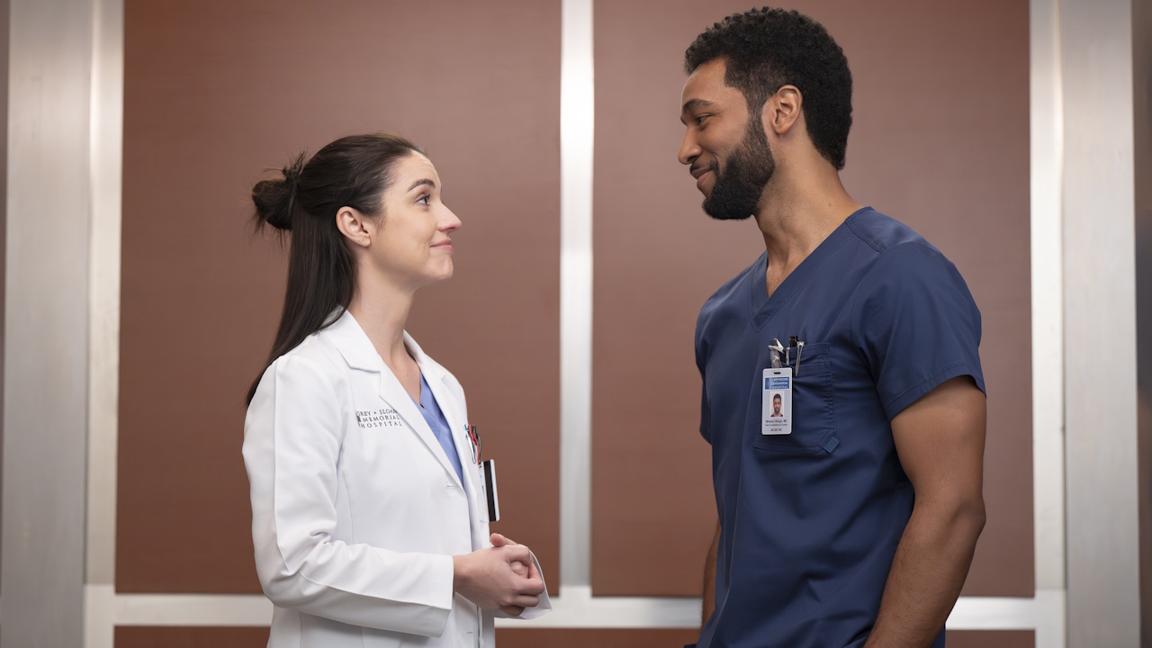 Jules Millin and Winston Ndugu (Adelaide Kane and Anthony Hill) smile at each other in an elevator on Grey's Anatomy.