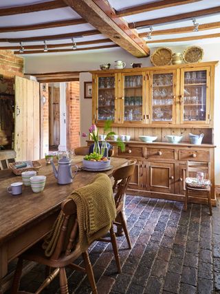Wooden table and chairs in front of a wooden dresser in a farmhouse kitchen