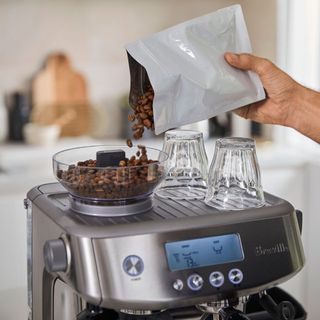 coffee beans being poured into a coffee maker