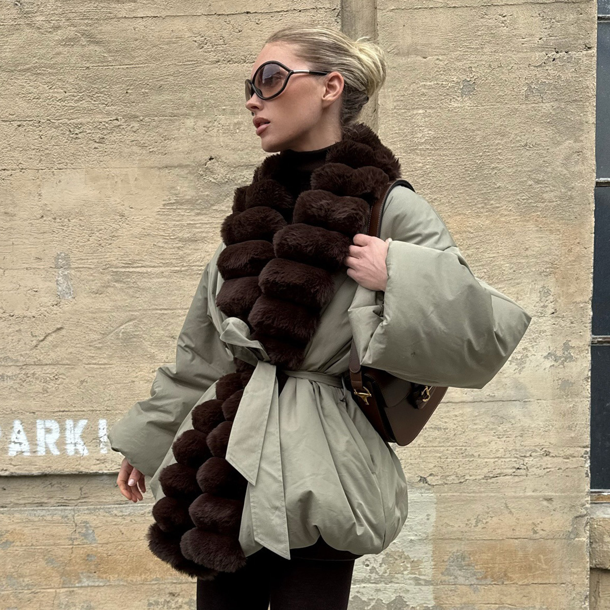 Elsa wears a fur-trimmed coat with a brown gucci bag.