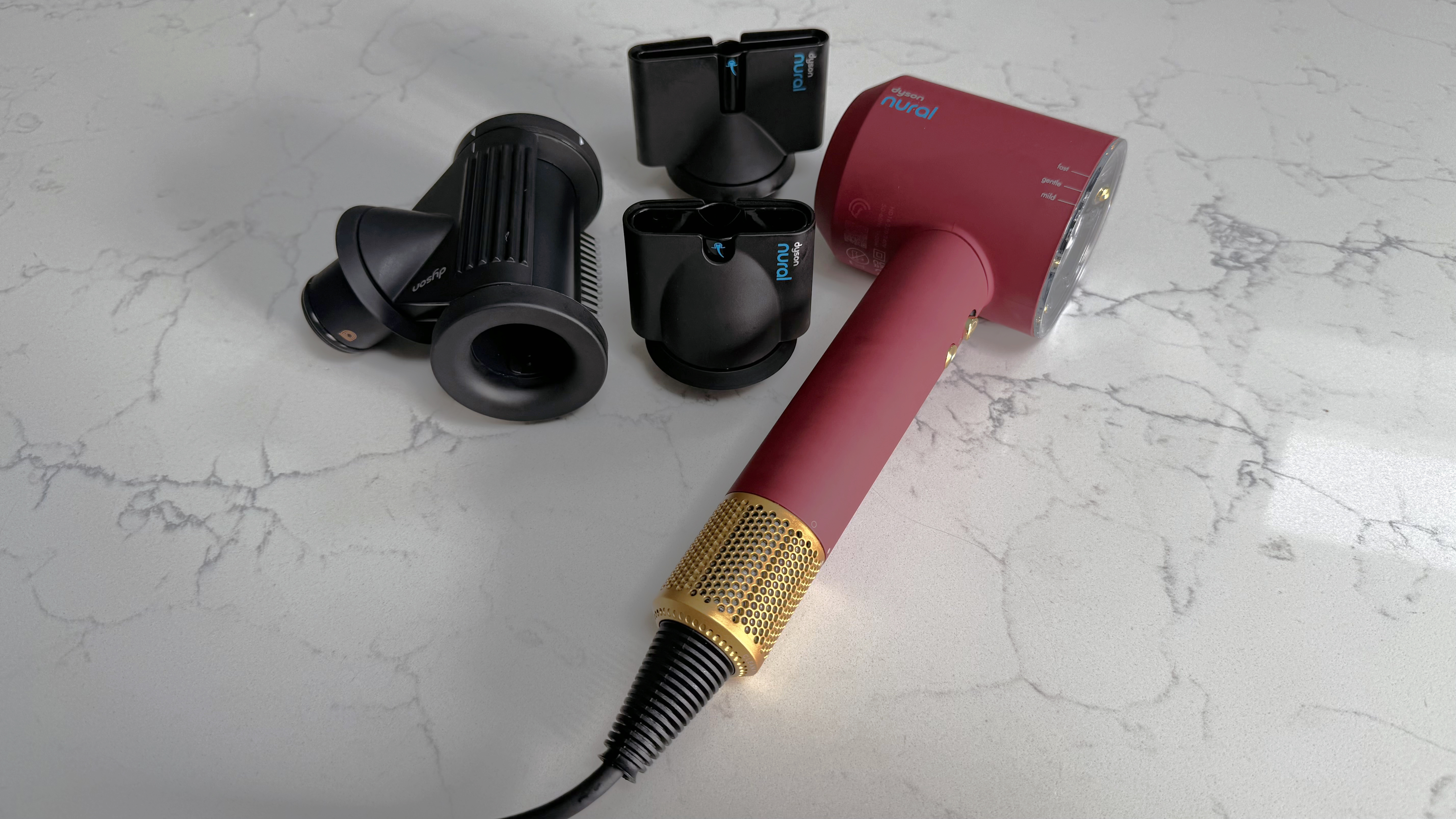 Dyson Supersonic Nural hair dryer with five magnetic styling attachments on a worktop