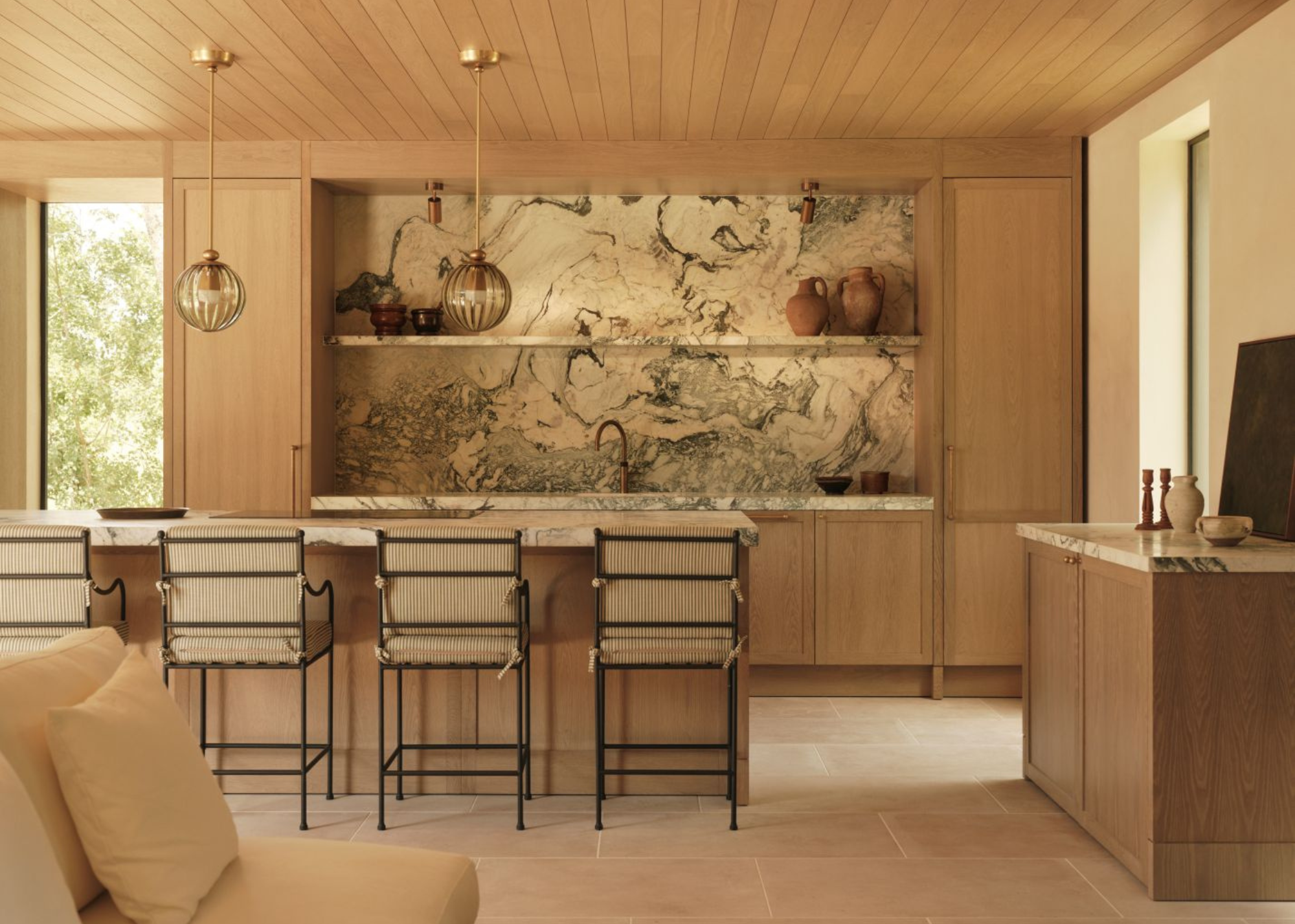 an open plan kitchen completely clad in timber with striking blue veined marble backsplash and counters
