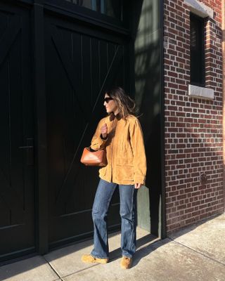 Anna wears barn jacket, jeans, and suede shoes.