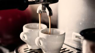 An espresso machine filling two cups of coffee with an espresso