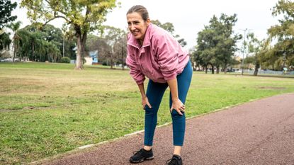 Woman in running clothes bent over with her hands on her knees