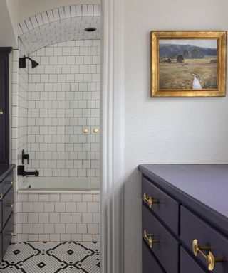 Hallway-with-gold-leaf-framed-landscape-art-looking-onto-white-tile-bathroom-in-the-distance-with-archway-