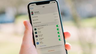 Someone holding an iPhone 11 displaying the iCloud info screen