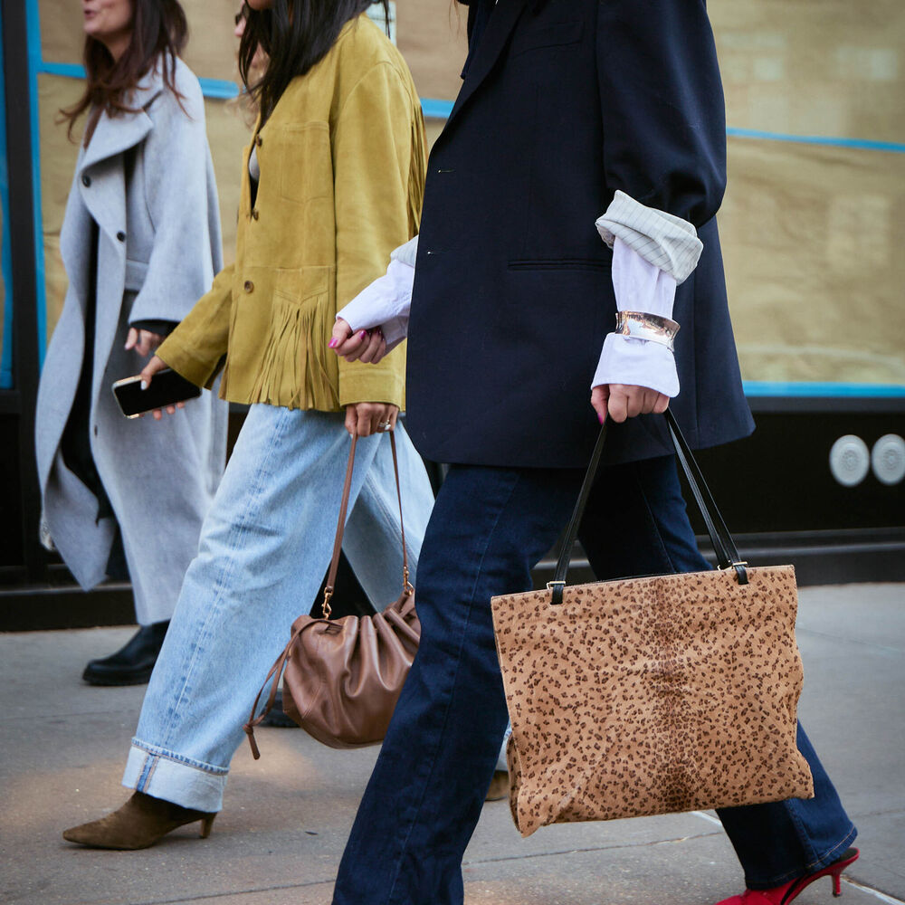 Women are walking while wearing jeans, jackets, and handbags